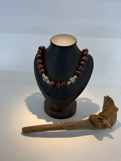 A red and dark beaded necklace on a jewelry display bust